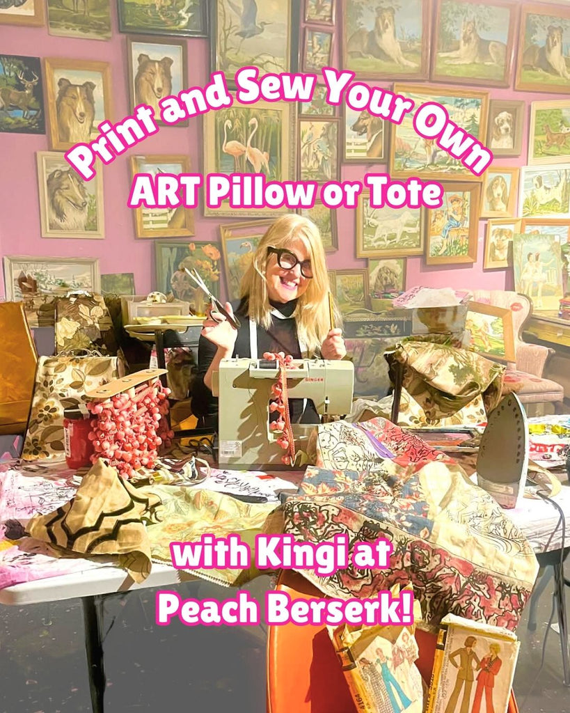 Person at a table with sewing materials and art supplies, surrounded by framed pictures on a pink wall.